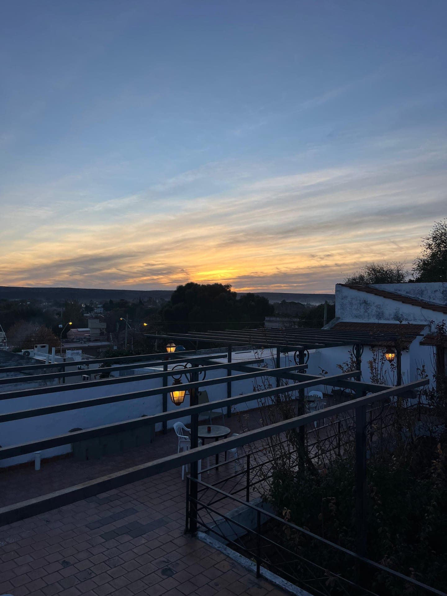 Mesas y sillas en la terraza con pergolas a la caida de la tarde