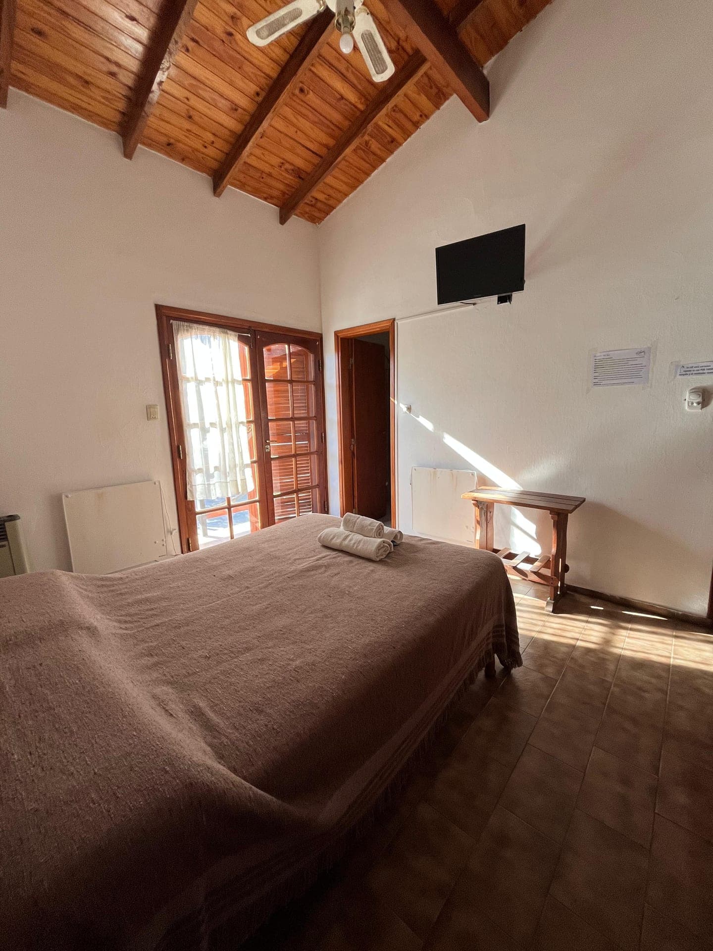 Habitacion con television, calefactor y puerta ventana de madera al balcon