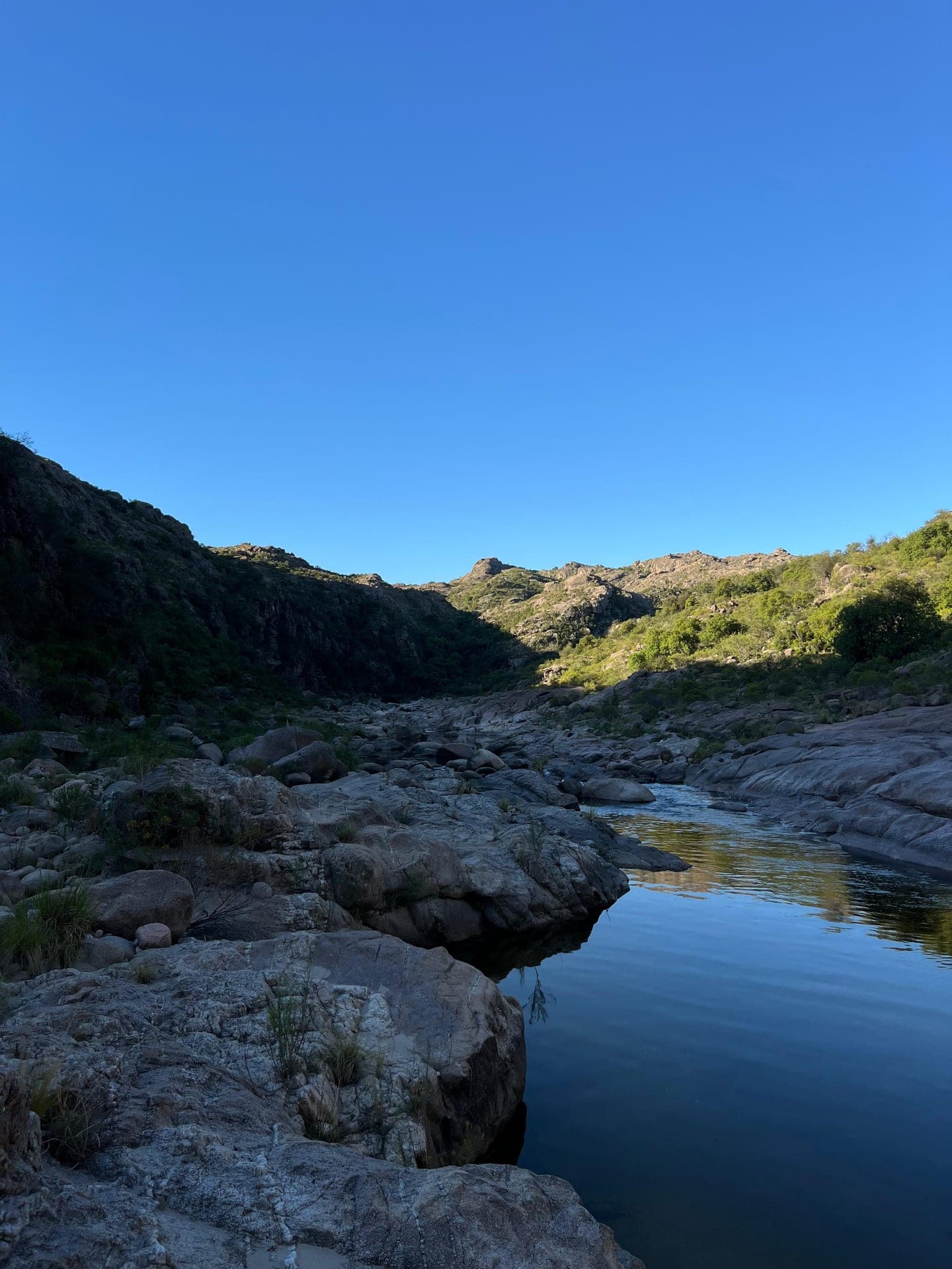El rio entre grandes piedras y las sierras de fondo